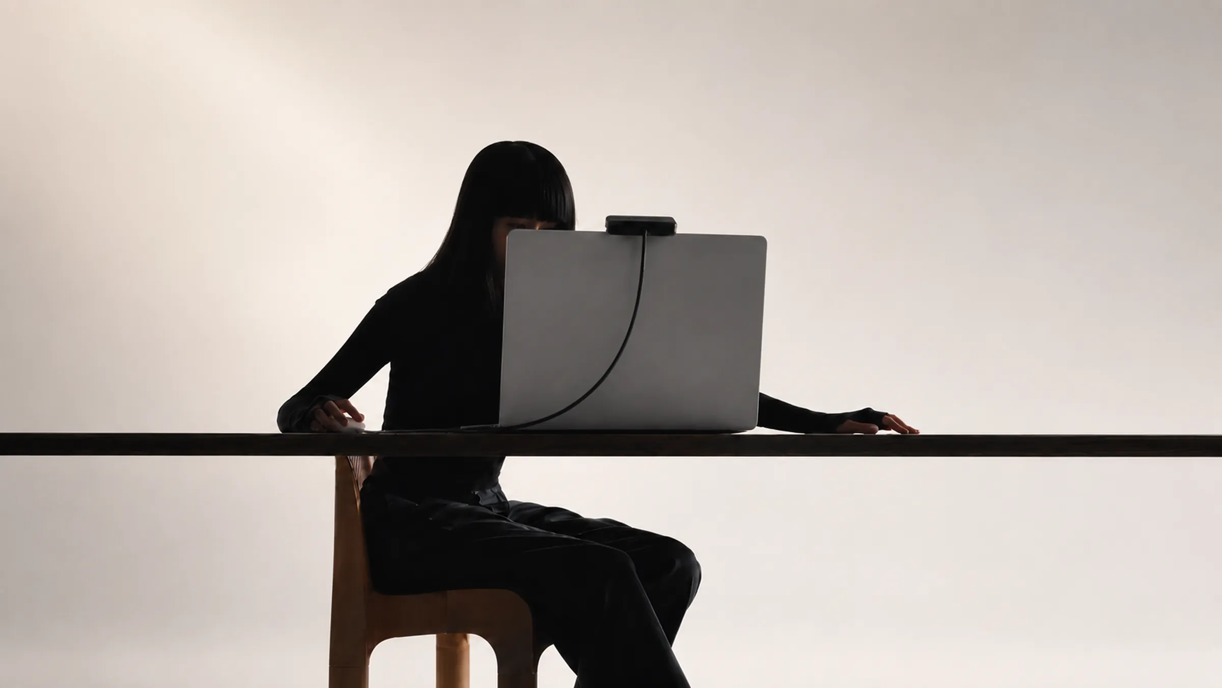A person working at a laptop with the Archetype device mounted on the screen